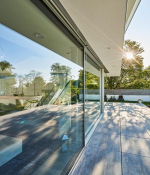 Modern luxury villa exterior with big glass windows and wooden terrace